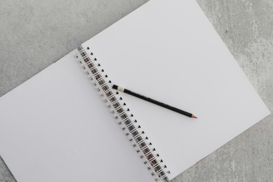 Open notebook and pen resting on a wooden desk